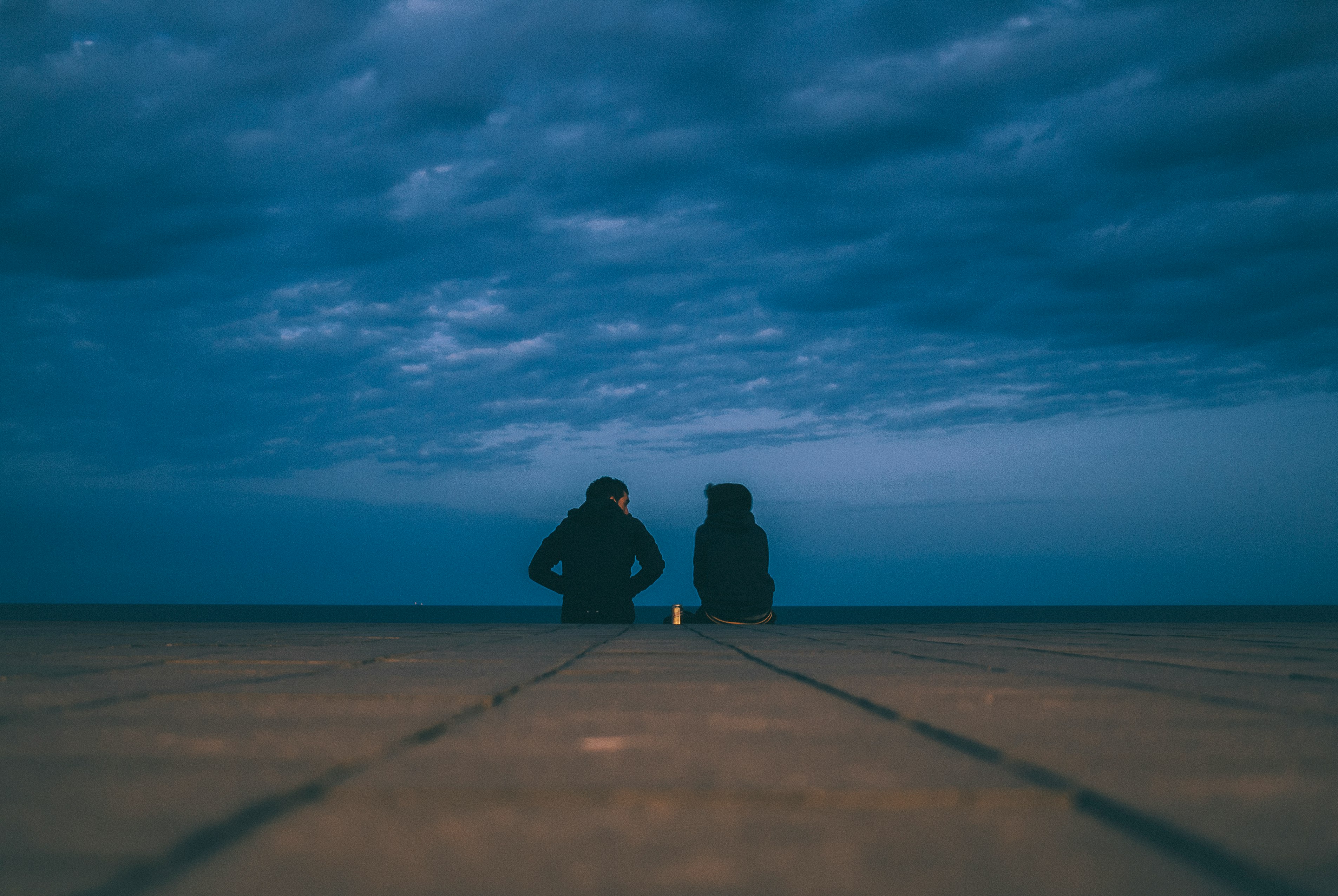 two people wearing black jackets sitting on floor